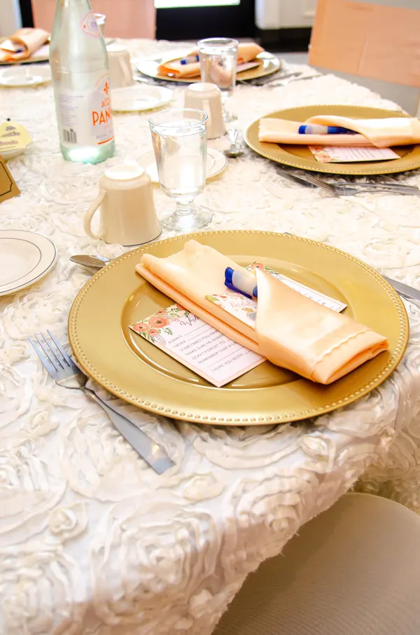 Place setting with gold plate on textured white tablecloth